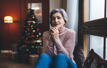 Smiling mature woman resting next to window