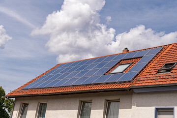 Red tile roof with window almost completely covered with solar panels