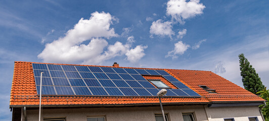 Red tile roof with window almost completely covered with solar panels