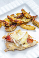 poultry meat grilled with parma ham and brie cheese served with roasted potatoes