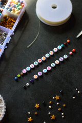 Friendship bracelet letter beads and various other jewelry making supplies on dark background. Selective focus.