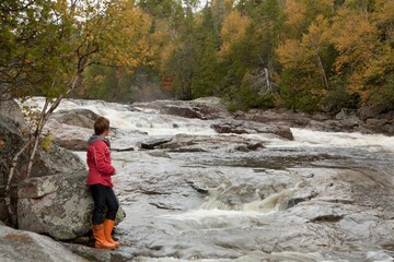 Obraz premium A Woman Stands Along The Riverbank; Ontario, Canada
