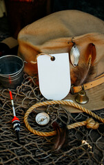 Fishing theme. Label on fisher cap with hooks, bucket, fishing buoy, compass and fish string on wooden background. Free space