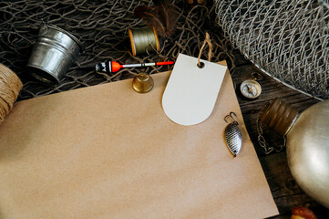 Vintage paper for your text logo. Fishing tackles, cap, net, bucket on a wooden background.