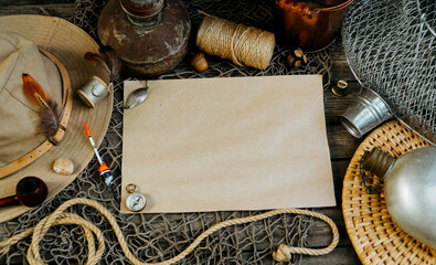 Vintage paper for your text logo. Fishing tackles, cap, net, bucket on a wooden background.