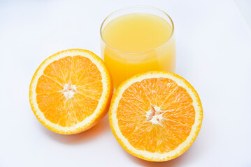 Orange juice in a glass glass and the fruit of oranges. Refreshing drink on a white background of fruit.