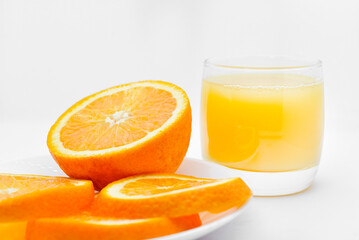 Orange juice in a glass glass and the fruit of oranges. Refreshing drink on a white background of fruit.