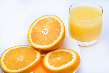 Orange juice in a glass glass and the fruit of oranges. Refreshing drink on a white background of fruit.