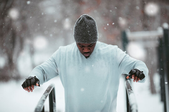 Young African American man getting ready to do dips and exercise in an outdoor park during winter and snow