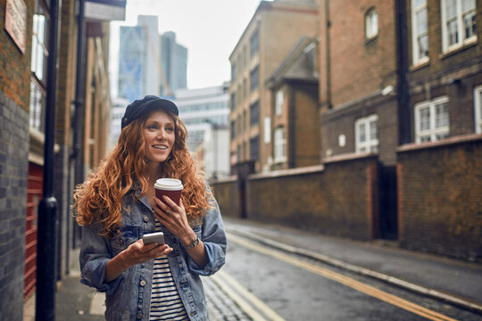 Young Caucasian woman using a smartphone while walking in the streets of London UK