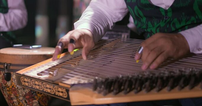 A man playing on traditional oriental musical instrument qanun during music concert. Performers playing music for audience. Close-up shot