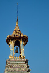 Fototapeta na wymiar A resplendent Thai temple bell tower, crowned with a gleaming golden roof and adorned with vibrant details, stands proudly against the backdrop of a flawless blue sky.