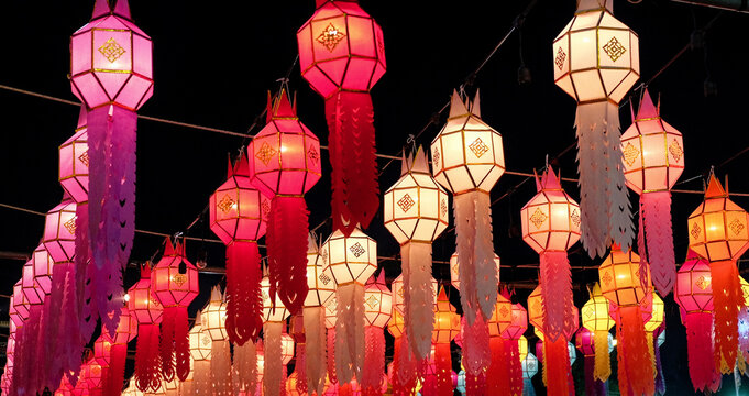 A festive display of colorful, illuminated paper lanterns hanging against a dark backdrop.