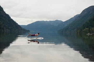 A Young Man Leaps Onto His Body Board In Cameron Lake; British Columbia Canada