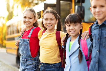Group Of Multiethnic Happy Kids Standing Outdoors Near School Bus