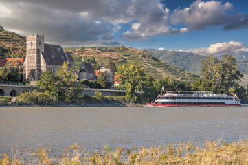 Panorama of Wachau valley (Unesco world heritage site) with ship on Danube river against Sankt Michael church in Lower Austria, Austria