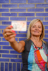 a smiling mature woman showing her ID. Spanish national identity document. Personal and...