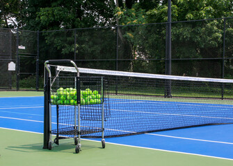Blue tennis court with a cart of tennis balls