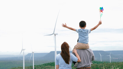 Concept of progressive happy family enjoying their time at the wind turbine farm. Electric...