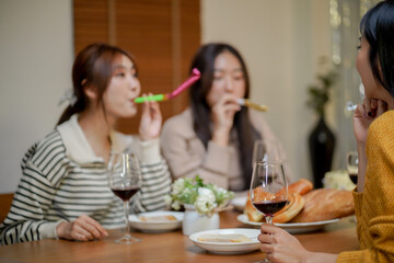 Cheerful friends enjoying home Birthday holiday party. Asian Friends cheering drinking red wine celebrating New Year party.