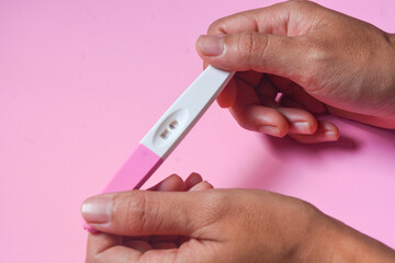 Close up of a tool for checking pregnancy that is being opened and marked with 2 lines