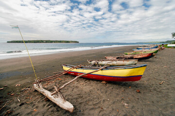 Volcanic black sand beach and fishing canoes on the coast of Malekula Island, near the village of Walarano, Vanuatu