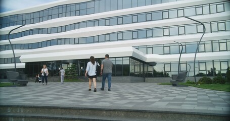 Courtyard of modern medical facility. Medical staff and diverse people enter and exit the hospital....