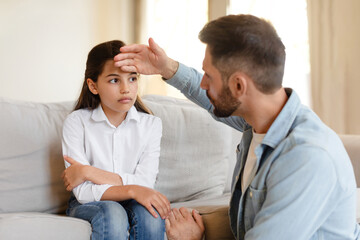 Father Caring For Sick Daughter With Fever Touching Forehead Indoor