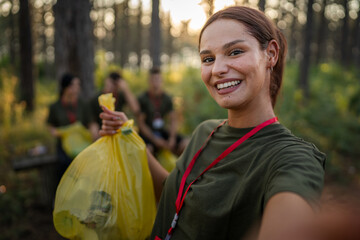 Portrait of caucasian female teenager activist volunteer during picking up waste garbage plastic...