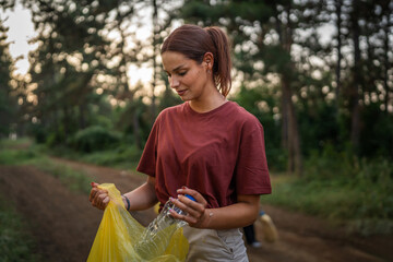 Portrait of caucasian female teenager activist volunteer during picking up waste garbage plastic...