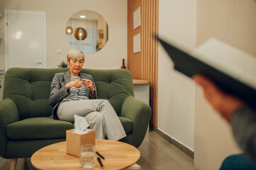 A depressed senior female patient is sitting in a doctor's office.