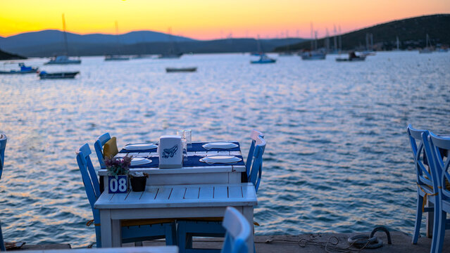 romantic Dinner table, Sunset Orange sky and sailboat waiting in the calm sea, Sunset view in Fethiye bays, Calmness and meditation