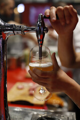 waiter filling beer glass from draft tap