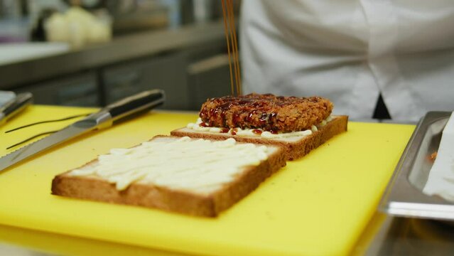 Chef cooking Katsu Sando japanese sandwich with breaded beef or pork chop, cabbage and tonkatsu sauce, traditional Japanese cuisine in restaurant.