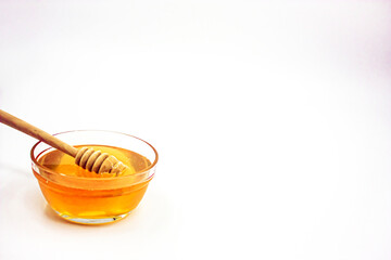 Glass bowl full of honey and wooden honey spoon inside the honey. Photograph.