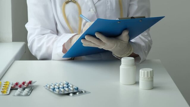 Female doctor filling up medical form at clipboard in clinic and talking with patient. Physician taking an anamnesis or patient's personal medical history. Health care, medicine concept