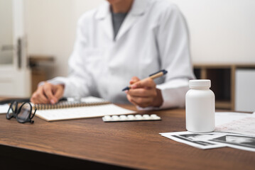 female doctor close-up medication prescription at table with ultrasound images, jar of pills. documenting medical details. 