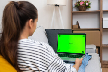 Brunette woman with long ponytail rests looking at laptop screen with chromakey female browses...