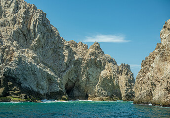 Fototapeta na wymiar Mexico, Cabo San Lucas - July 16, 2023: South view on Reserva de Los Marina channel between tall gray boulders in greenish ocean water. 