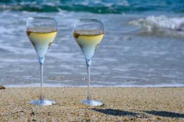 Summer time in Provence, two glasses of cold champagne cremant sparkling wine on sandy beach near Saint-Tropez in sunny day, Var department, France