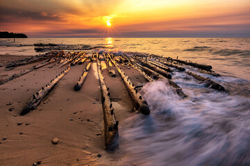 Lake Superior sunset over shipwreck timbers as waves roll in.
