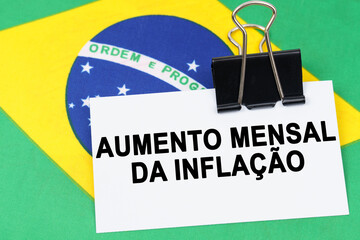 On the flag of Brazil lies a business card with the inscription - monthly rise in inflation
