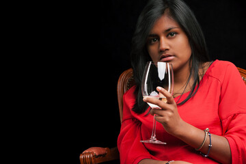 Woman in red cherishes wine's scent, seated