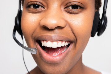 Close up shot on beautiful white smile. Afro american woman in call centre working receiving call...