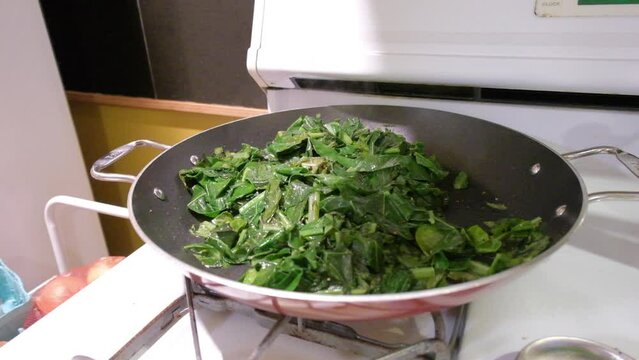 cooking collard greens in a pan on the stove in the kitchen