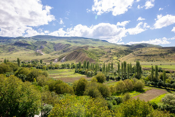 Fototapeta na wymiar Mtkvari river valley landscape in Samtskhe - Javakheti region, Georgia with Lesser Caucasus mountains, green vegetation and vineyards, view from Aspindza town.