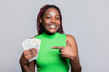 Delighted African American woman with colourful braids smiling holding cash dollars bunch of money...