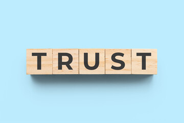 Trust wooden cubes on blue background