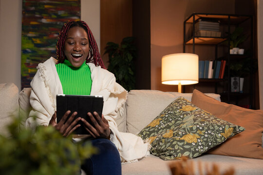 Happy surprised smiley afro american woman with colourful barids reading news on tablet smiling