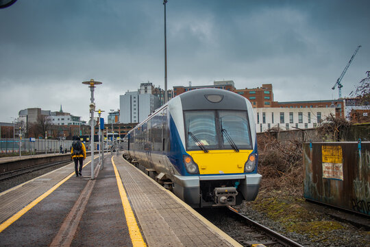 Diesel train at the Great Victoria street station in Belfast, northern ireland. View towards the train track main office building on a cloudy day.